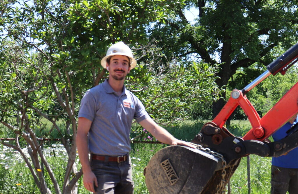 Dig crew member next to an excavator